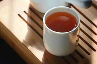 白杯盛热茶置于木托盘上