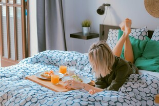 床上惬意享用早餐的女子