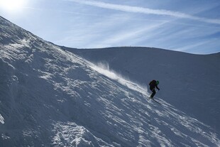 单人滑雪于雪山陡坡间