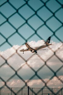 透过围栏看空中飞行飞机
