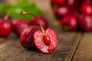 切开的鲜红樱桃摆于木桌