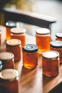 木桌上排列的蜂蜜玻璃罐