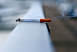 一支点燃的香烟置于栏杆上