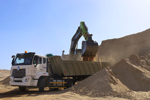 挖掘机向卡车装载沙土