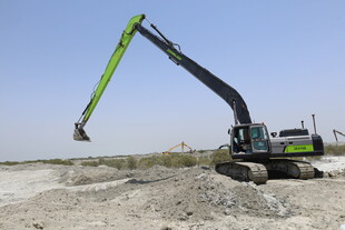 绿色挖掘机于沙地作业