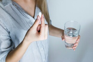 女性手持药片与水杯