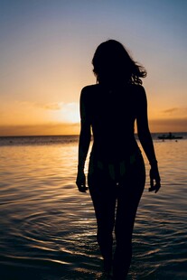 夕阳下海边漫步的女性身影