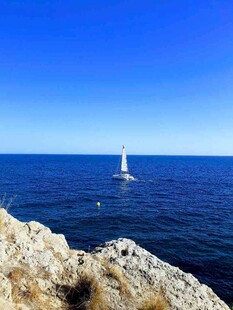 海边岩石旁的远航帆船