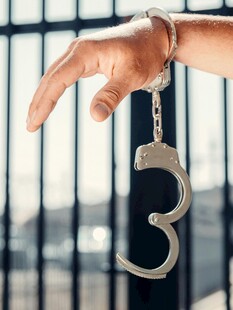 手戴手铐于铁栏前