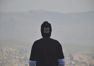 蒙面人立于开阔风景前