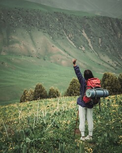 徒步者于绿野间伸展双臂