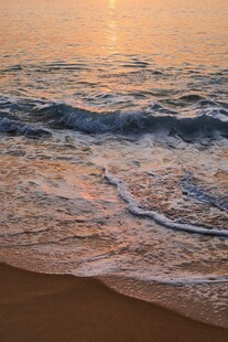 夕阳下的海浪轻拍沙滩