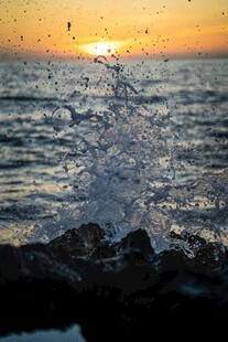 夕阳下海浪拍打礁石瞬间