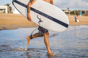 男子海边扛冲浪板踏浪