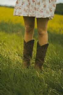 女孩草地中穿着碎花裙与靴子
