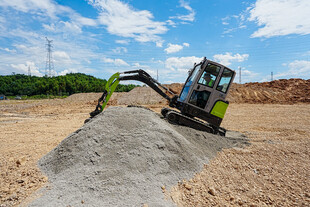 挖掘机作业于砂石堆旁