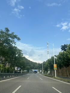 宽阔公路旁绿树蓝天白云