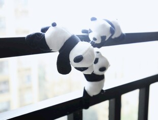 阳台栏杆上的可爱熊猫玩偶