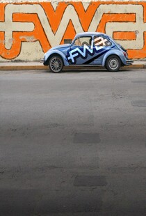 蓝色赛车停于橙色背景前