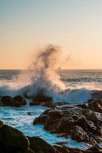 夕阳下海浪拍打礁石美景