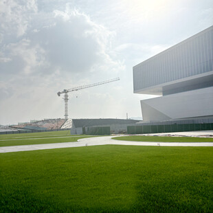 现代建筑旁的绿地与塔吊