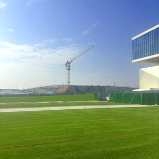 户外绿茵场与远处建筑塔吊