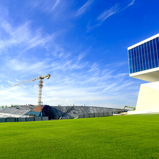 蓝天绿地旁的建筑施工场景