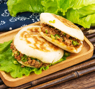 美味肉馅烧饼摆于木盘上