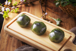 三个青团摆放在木砧板上