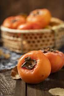 木桌上竹篮里的新鲜柿子