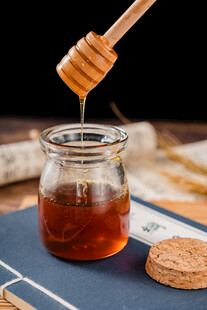 蜂蜜从木勺滴入玻璃罐中