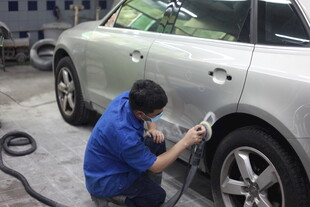 工人专注进行汽车喷漆作业