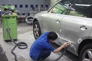 工人专注维修银色汽车
