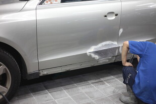 工人专注修复汽车凹陷处