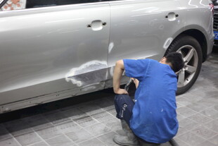 工人专注修复银色汽车划痕