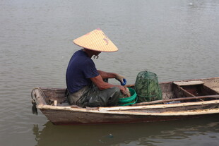 水乡渔夫驾舟整理渔具