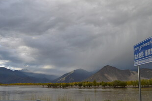 高原路旁阴云下的山水景