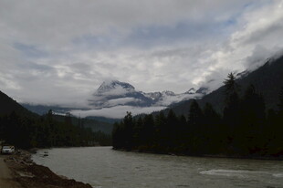 山间河流与远处云雾缭绕山峰
