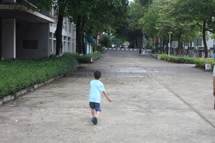 小孩独自走在宽敞道路上