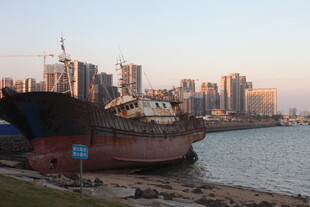 岸边旧船与城市天际线