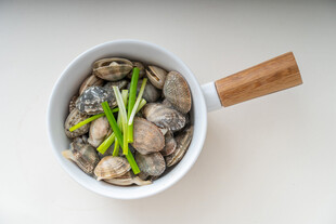 白锅中的蛤蜊与葱段