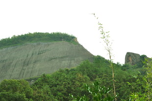 青山绿树环绕的陡峭崖壁