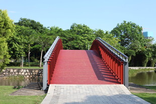 红色拱桥横跨绿意湖畔