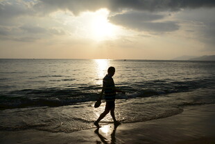 夕阳下海边独自行走的人