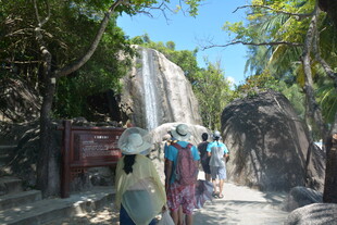 游客漫步于瀑布旁的小径