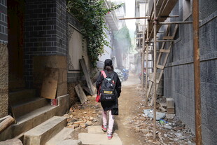 女孩穿行于狭窄破旧小巷