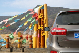 藏区路旁的汽车与经幡景观