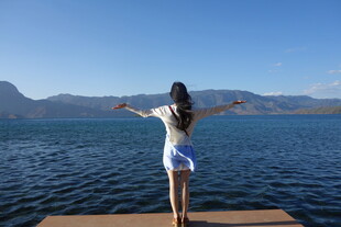 女子于湖畔栈桥舒展双臂