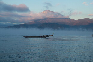 晨雾中孤舟静泊于山水间