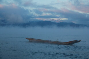 孤舟泛于云雾缭绕水面